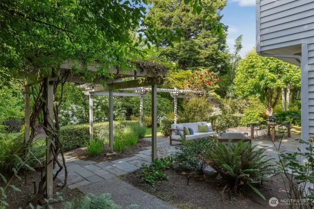The practical and elegant backyard features a large level patio, mature plantings and charming garden features.