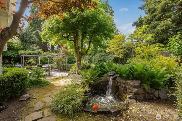 The practical and elegant backyard features a large level patio, mature plantings and charming garden features.