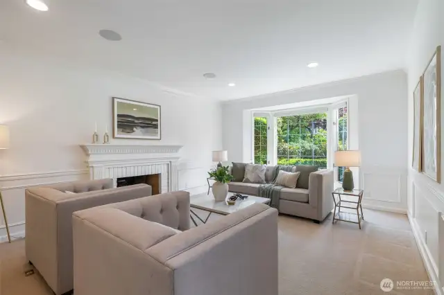 Bright living room with gas fireplace looking out to the manicured garden