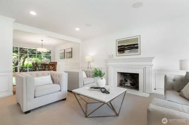 Bright living room with gas fireplace looking out to the manicured garden