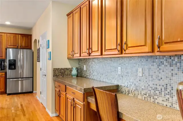 A wall of attractive wood cabinets crafted from rich, natural wood frame an informal desk area and offers additional counter space.