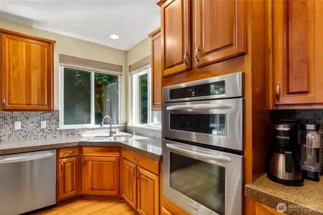 This kitchen exudes warmth and elegance. It has a timeless feel with granite counters, stainless appliances and a corner kitchen sink with a soothing view of the green space.