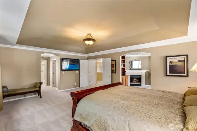 Architectural ceiling details add a designer touch.  The sitting room is to the right, two walk-in closets and the primary bath are to the left of the TV.