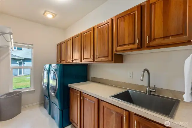 Large laundry room with beautiful wood cabinetry, plenty of counter space, a sink and hanging rack.  The washer and dryer convey with the home.