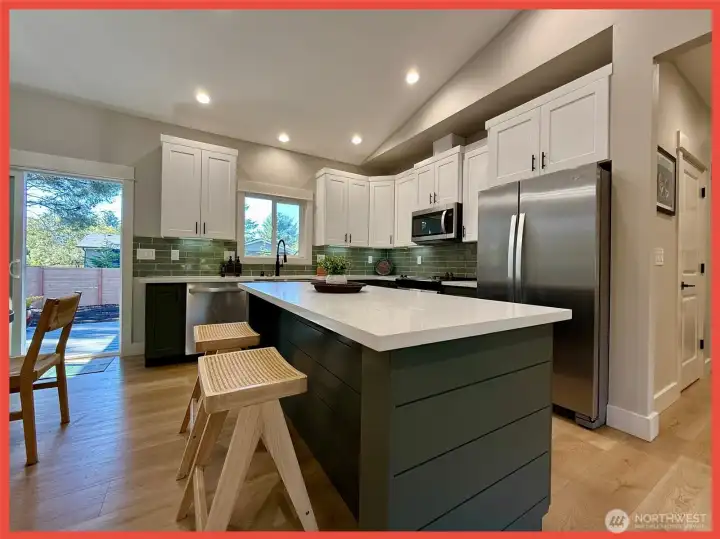 The kitchen features gorgeous cabinetry, stainless steel appliances, Quartz slab countertops, tiled backsplash, farm sink,  and island/breakfast bar.