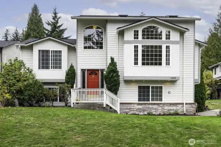 Bright 3-story home with large arched windows, and manicured lawn and 3 car garage