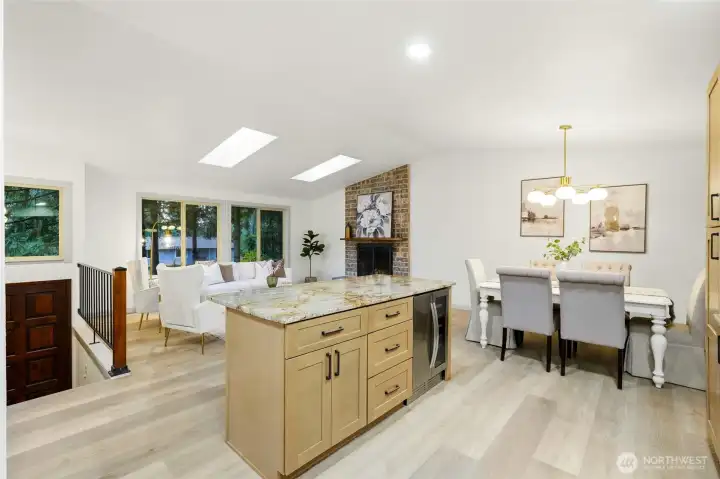 Completely open-concept kitchen, dining and living room with new paint, LVP, bright skylights and fireplace