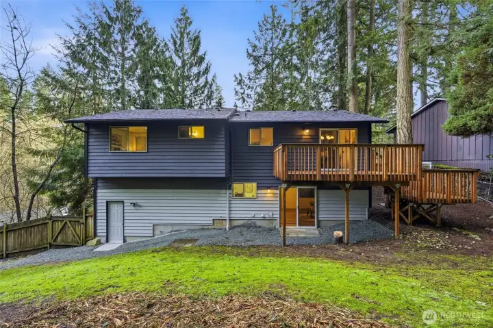 The freshly cleared backyard reveals modern exterior paint, the lines of a two-level deck and a new French drain