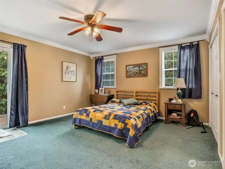 Main level primary bedroom with sliding glass door and private deck