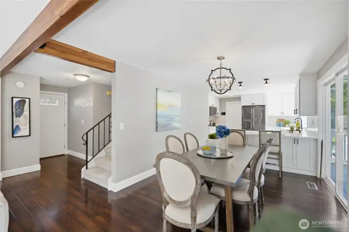 Spacious dining area with warm wood beam accents and seamless flow to the kitchen and living spaces.