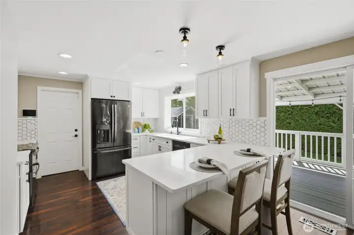 Remodeled kitchen featuring quartz countertops, soft-close cabinetry, black stainless steel appliances, and a peninsula with bar seating.