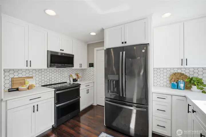 Abundant cabinetry, tile backsplash, and black stainless steel appliances create a stylish and functional workspace.