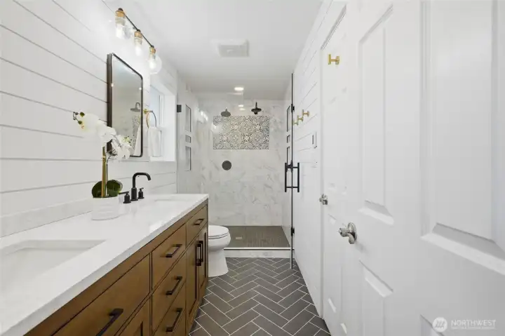 Remodeled bathroom with dual-sink vanity, tile flooring, and convenient access from both the hallway and bedroom.