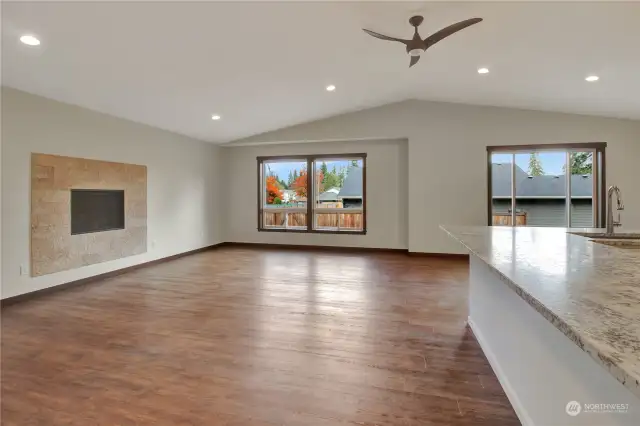 Open concept living with vaulted ceilings, large windows, gas fireplace, and spacious upgraded kitchen appliances and cabinets.