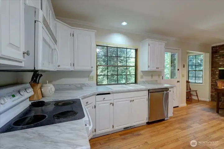 Window at sink overlooks back yard and out to lovely trees! Backyard also accessed from kitchen door. Really beautiful, peaceful view.