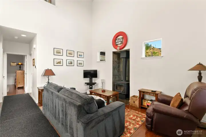 Comfortable living area featuring a freestanding wood-burning stove, perfect for chilly evenings. Tall ceilings and natural light create an inviting space.