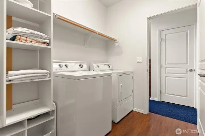 Main floor laundry room with washer, dryer, and shelving for additional storage.