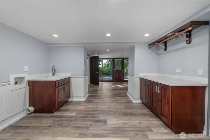 Downstairs offers a huge laundry area, and to the right of this photo is the downstairs family room with boxed ceilings and a gas fireplace. Straight ahead is a room that can be closed off if one wanted to, and a 3/4 bath along with access to the lower deck and yard.