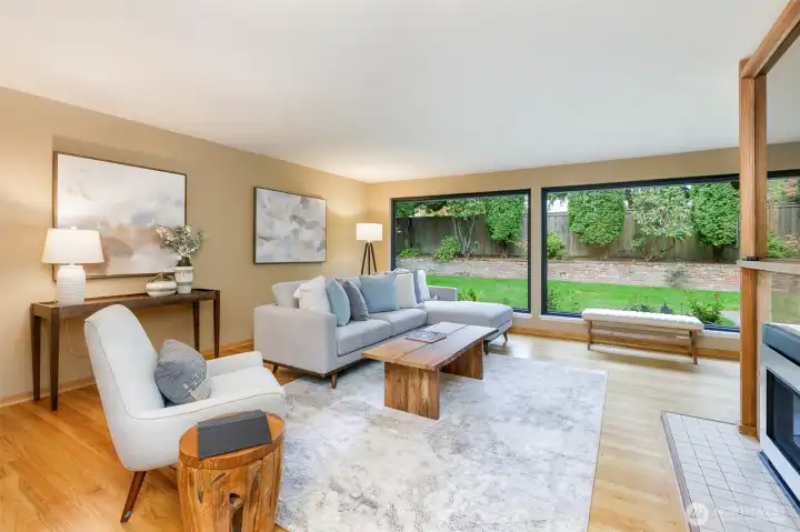 Open living room with hardwood floors, walls of windows, and garden views in Broadview Seattle home.