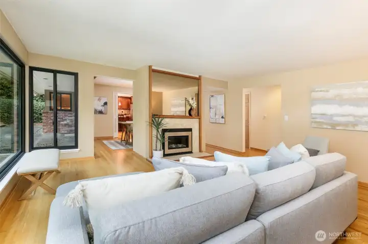 Open living room with hardwood floors, walls of windows, and garden views in Broadview Seattle home.