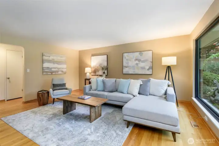 Open living room with hardwood floors, walls of windows, and garden views in Broadview Seattle home.