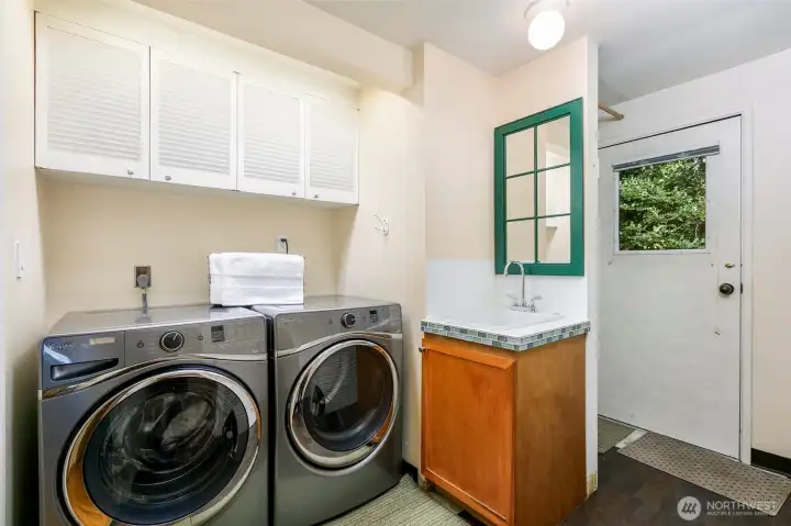 Spacious laundry room with sink and exterior door in Broadview rambler.