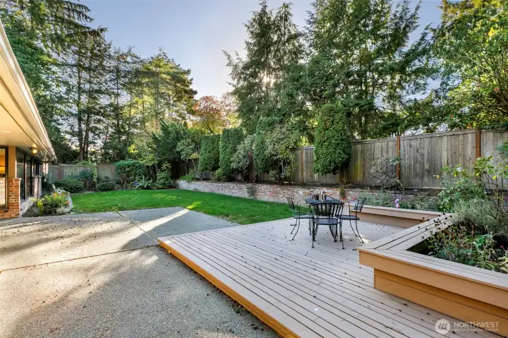 Private backyard patio and deck surrounded by lush gardens in Broadview Seattle home.