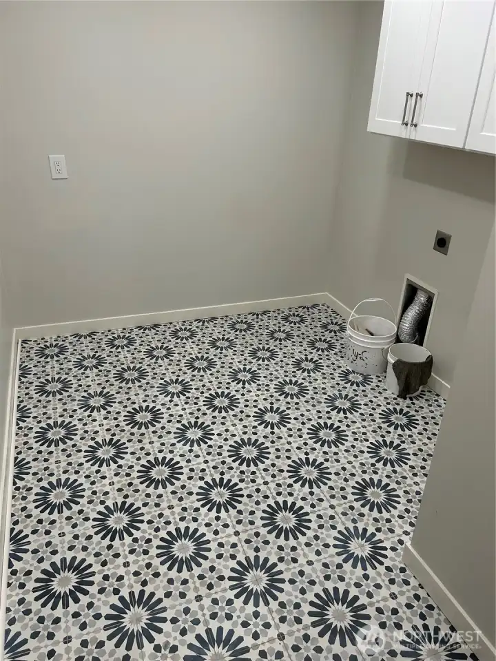The laundry room is spacious with washer and dryer hookups, plenty of space for extra cabinets or shelving, and a new floor that adds a fun touch to laundry day.