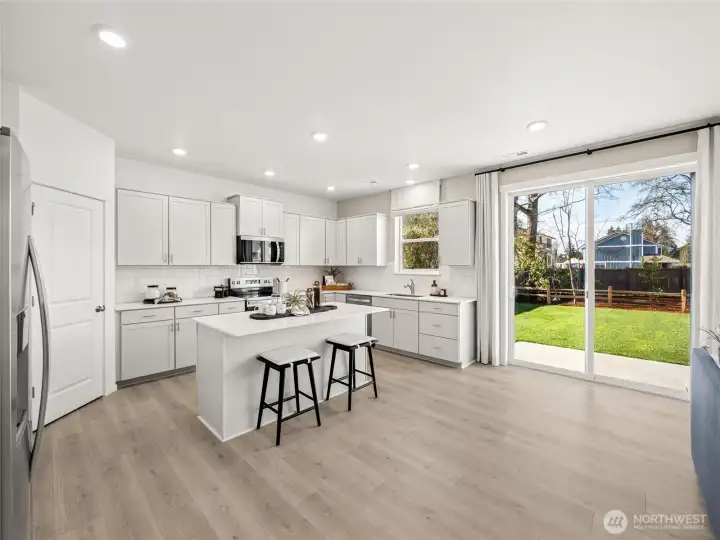 Open island kitchen with slab quartz counters, full height tile backsplash, soft-close cabinetry, and a walk in pantry.  Picture for representational purposes only, colors and features may vary.