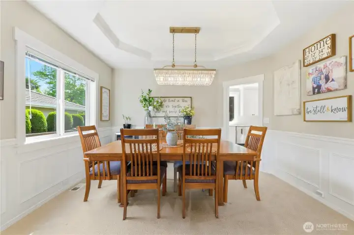 The elegant formal dining room continues the wainscoting and features a tray ceiling and a stunning chandelier.