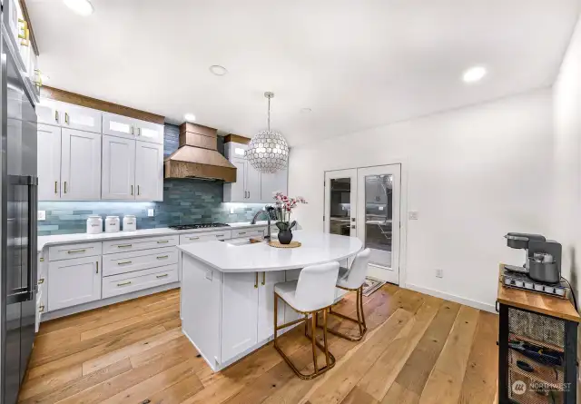 The gourmet kitchen boasts pristine white cabinetry, quartz countertops, and a central island with seating. Highlighted by a designer pendant light, this kitchen blends function and style.