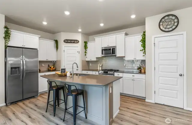 Beautiful white kitchen cabinets with grey quartz counter tops, tile backsplash.
