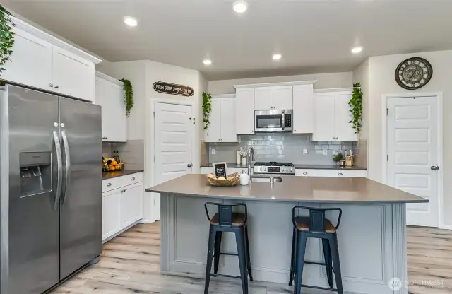 enough room for 4 or more at the counter - great gathering space. Stainless steel appliances compliment this light bright white & grey kitchen