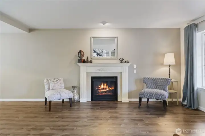 Cozy gas fireplace with large window looking out towards the front of the home.