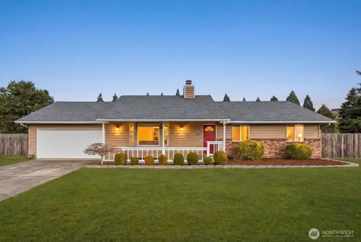 Single-level home with attached two-car garage, covered front porch, landscaped front yard, and fully fenced perimeter.