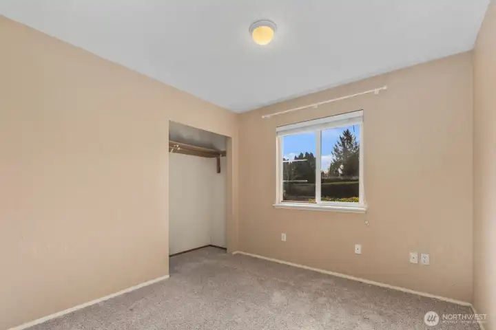 Bedroom with carpet flooring, open closet, and window overlooking fully fenced backyard