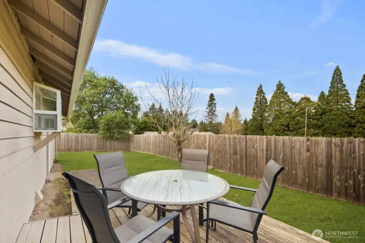 Inviting backyard retreat with a patio perfect for outdoor dining, a level grassy lawn, and full fencing for privacy