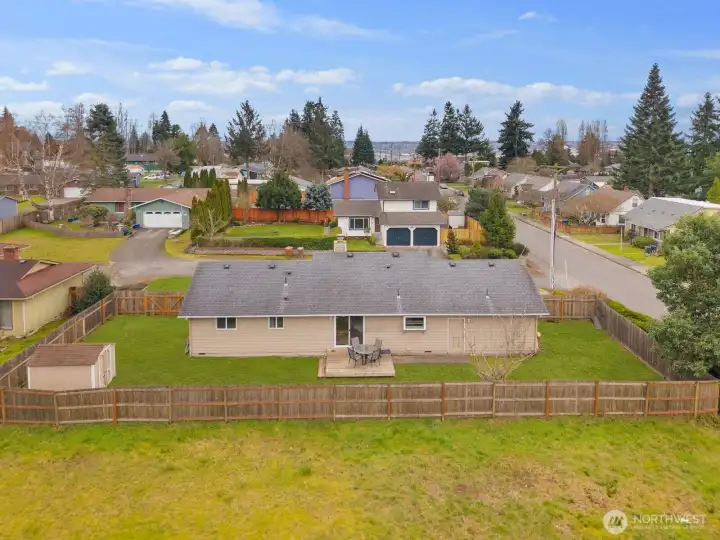 Drone view showcasing full fenced lot, patio area, and storage shed