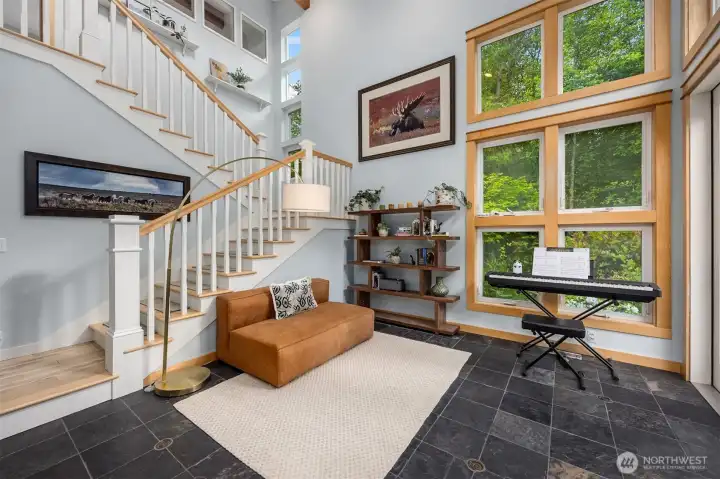Notice full 2 story windows in the den/office. The stairs lead to the upper level primary suite. French doors lead outside to a large patio area with a water feature and fencing for pets