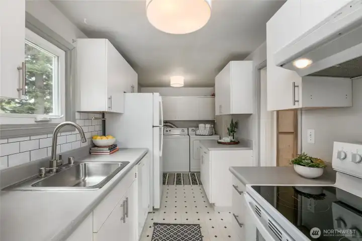 This photo is taken from the dining area looking back through the kitchen.  Notice the convenient laundry at the far end.  There is also a door that leads out to the deck.... How convenient is that for outdoor cooking and/or al fresco dining
