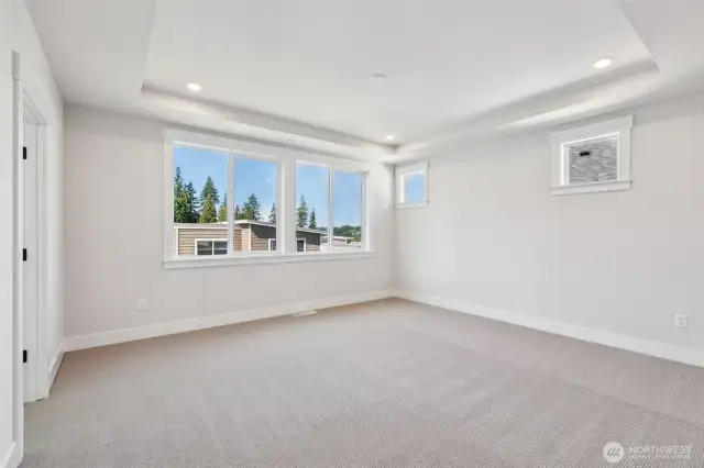 Primary bedroom adorned with a tray ceiling and is highlighted by partial Cascade Mtn. views.