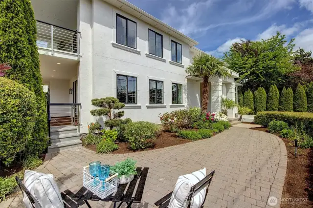 Striking curb appeal sets the tone for this stunning custom home highlighted by lush landscaping, rich greenery and designer pavers.