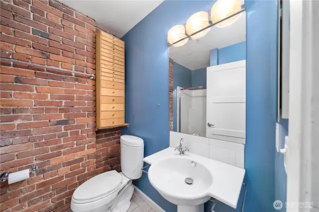 Guest bathroom with built-in storage, pedestal sink, tile floors.