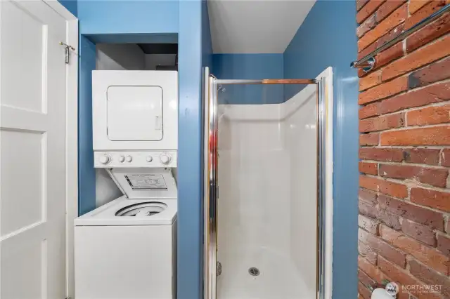 Other side of guest bathroom with stall shower and stacking washer-dryer.