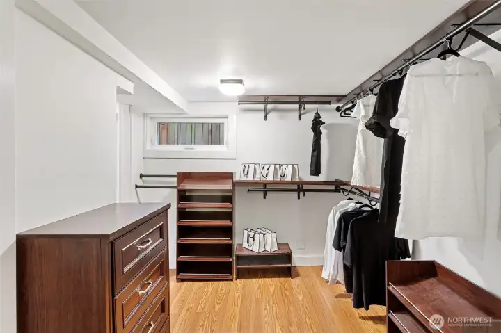 A large walk-in closet has built in drawers, racks and hanging bars to fit your entire wardrobe.