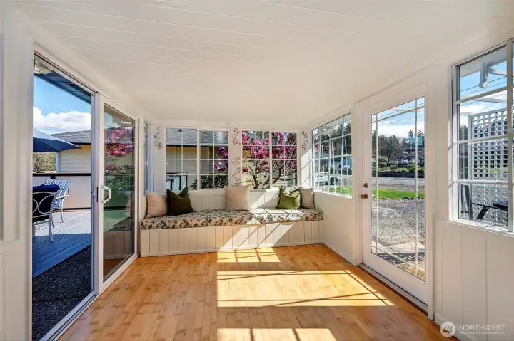 Just off the living room is this absolutely charming sunroom with built in seating that transitions seamlessly to a small bistro area to the right or to the large entertainment-sized deck In the back yard.