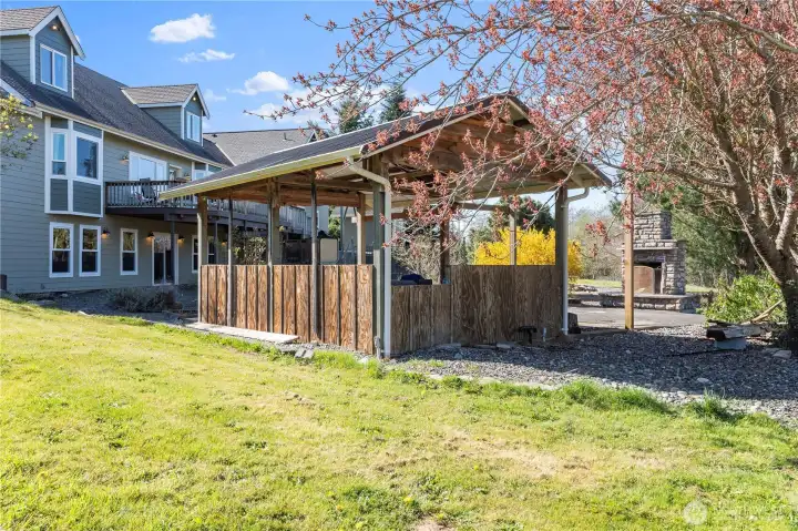 This outdoor cooking area/gazebo is roughed in for water and power. Wood fireplace to the right and a fire pit just beyond the fireplace.  Plenty of space to entertain outdoors.