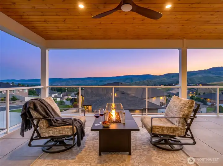 Expansive covered outdoor living space designed to capture sweeping mountain and valley views, creating a seamless extension of the home. The warm tongue-and-groove wood ceiling, modern gas fire table, and spacious lounge seating offer an inviting setting for year-round entertaining or quiet evenings overlooking the surrounding hills and city lights