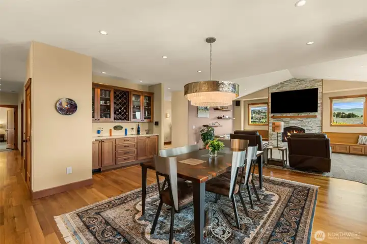 Refined open-concept living and dining spaces blend warmth, craftsmanship, and functionality with rich hardwood flooring, custom built-ins, and a beautifully integrated wine bar. The striking stacked stone fireplace anchors the great room,