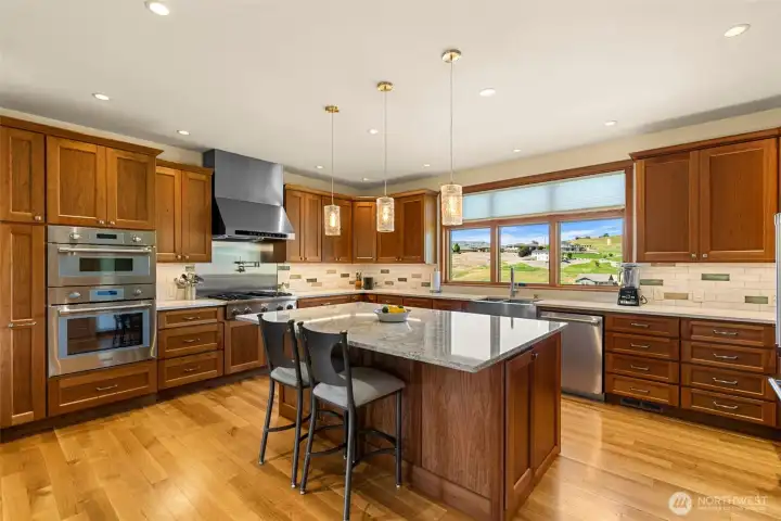 Beautifully appointed kitchen blending timeless craftsmanship with exceptional functionality. Rich custom cabinetry is complemented by elegant Cambria quartz countertops, a spacious center island, and warm hardwood flooring throughout.